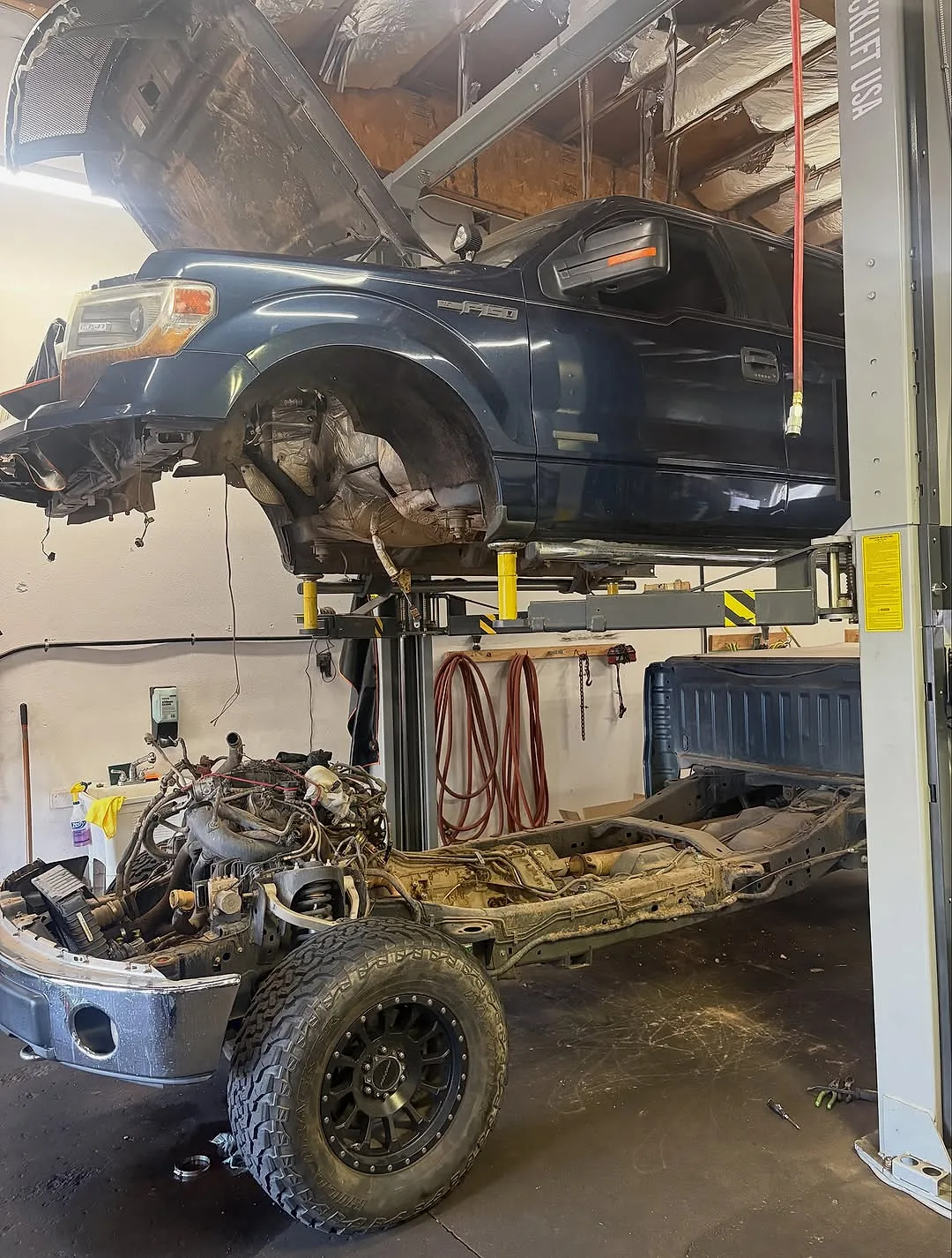 A Ford F-150 with its cab lifted off and the frame lowered to reach the exhaust manifolds at Mesa Auto & Fleet